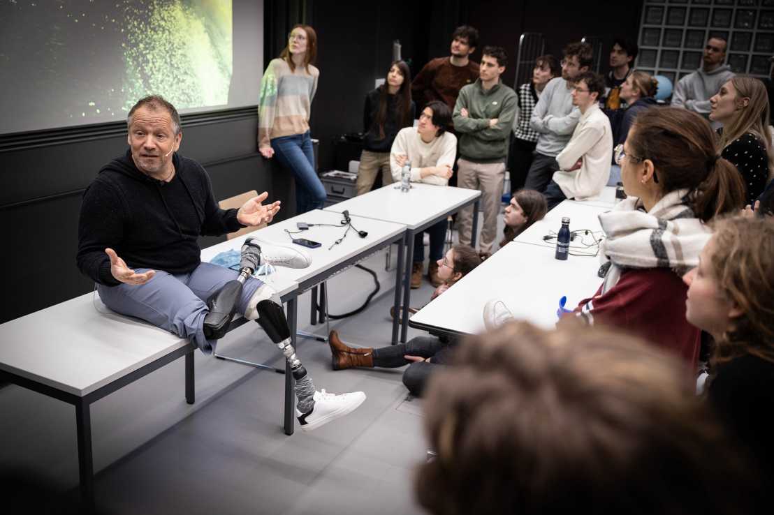 Enlarged view: Man with two prosthetic legs speaks in front of people during a workshop