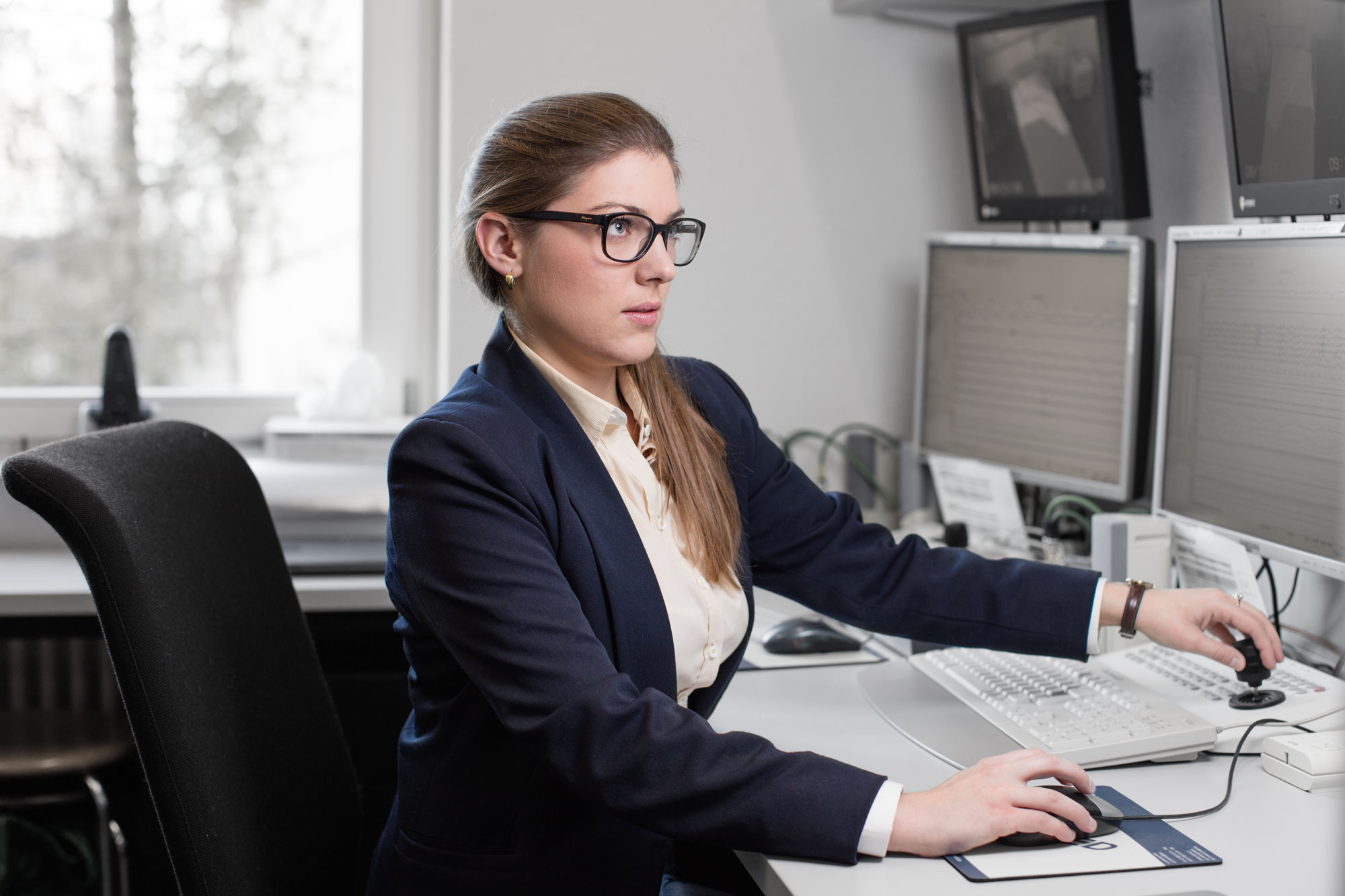 Enlarged view: Franziska Ryser infront of two Monitors moving a computer mouse