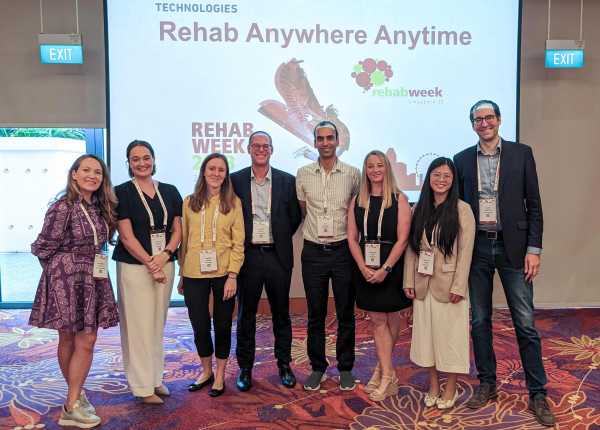 eight persons in front of a huge screen at rehab 2023 workshop