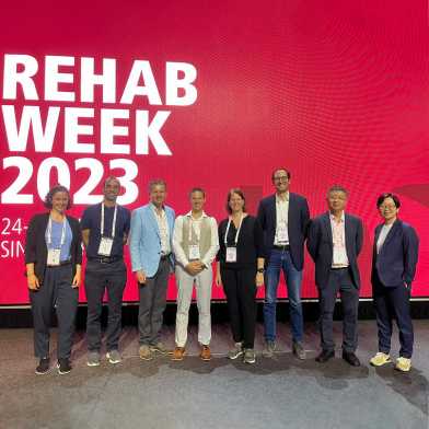 eight scientists in front of a huge panel at rehabweek 2023