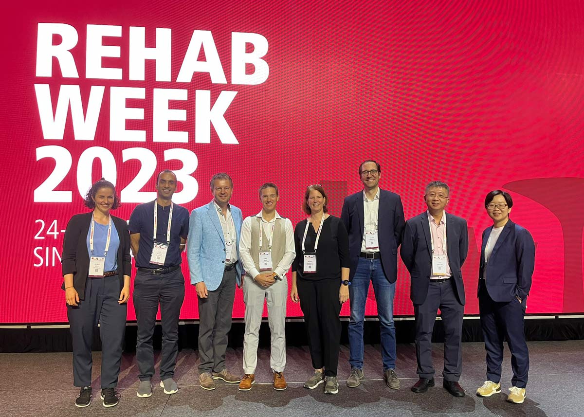 Enlarged view: eight scientists in front of a huge panel at rehabweek 2023