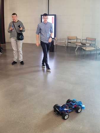 Enlarged view: Daniele, wearing headphones and navigating his remote-controlled car equipped with three sensors while a student is observing