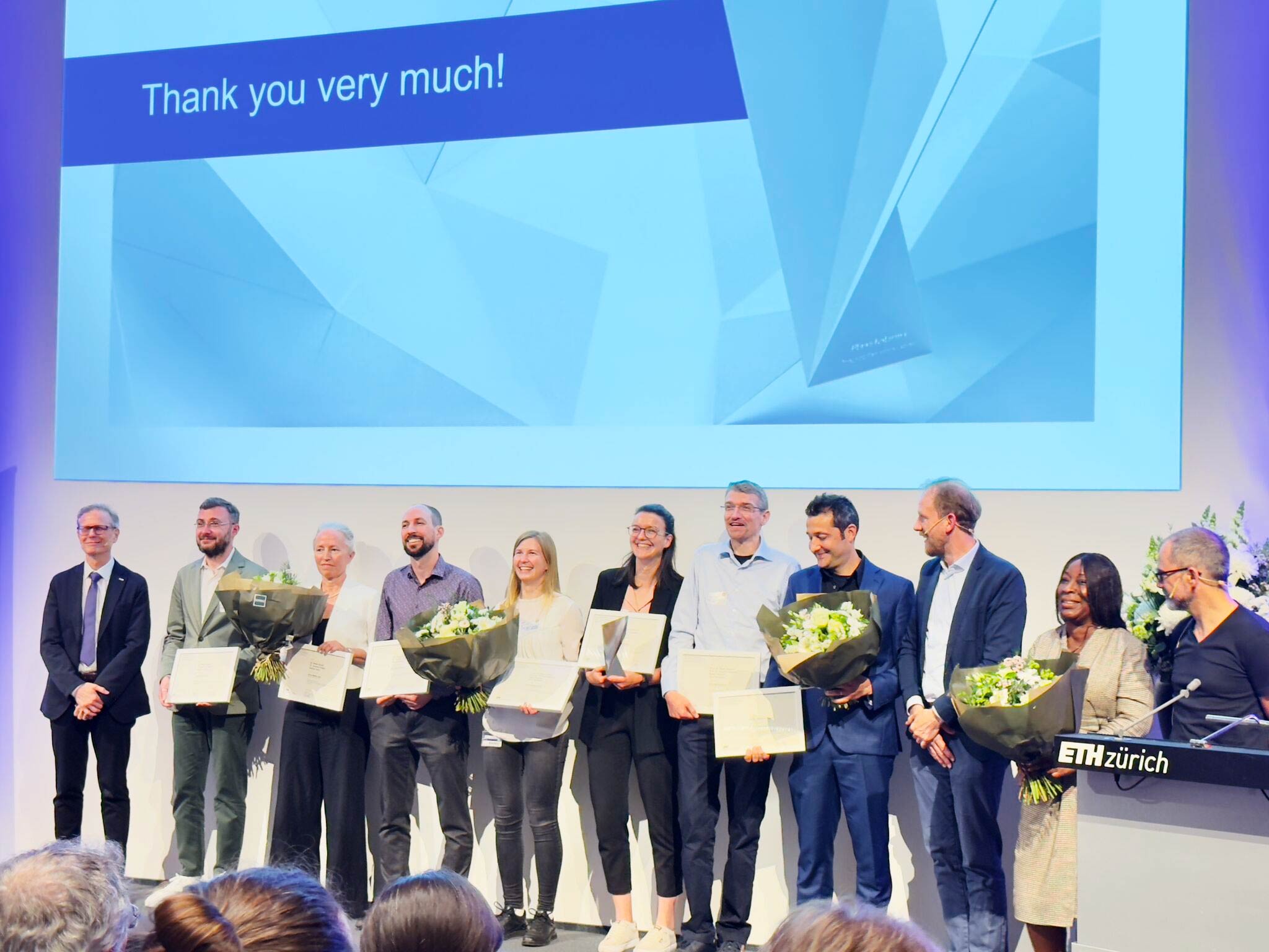 Enlarged view: Group of people in front of a roll up display with the text Kite Award